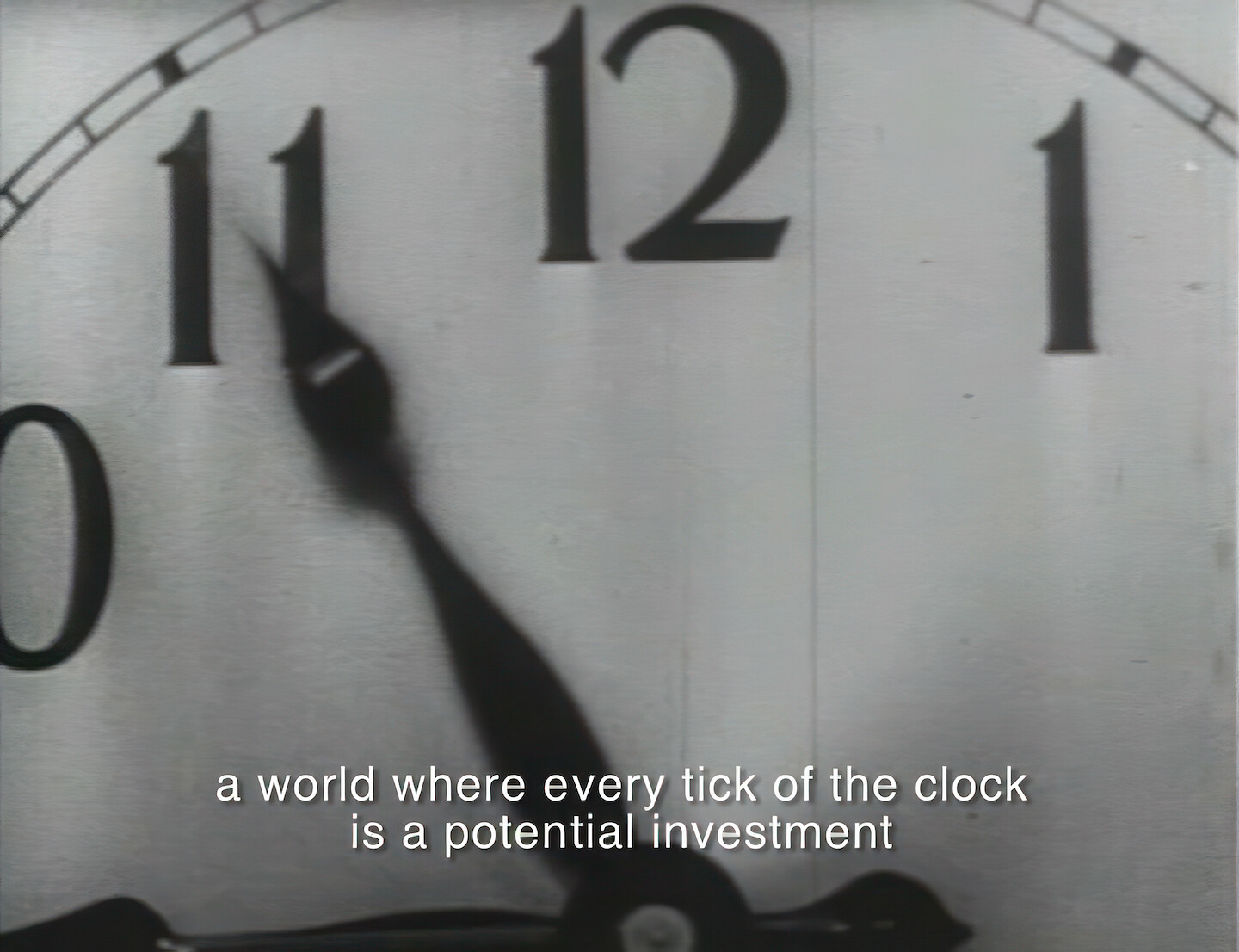 Film still depicting a close up of a clock. The minute hand is pointing at 11 and the hour hand is at 9. Subtitles say: a world where every tick of the clock is a potential investment.